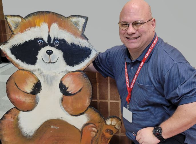  Man with arm around a wooden raccoon